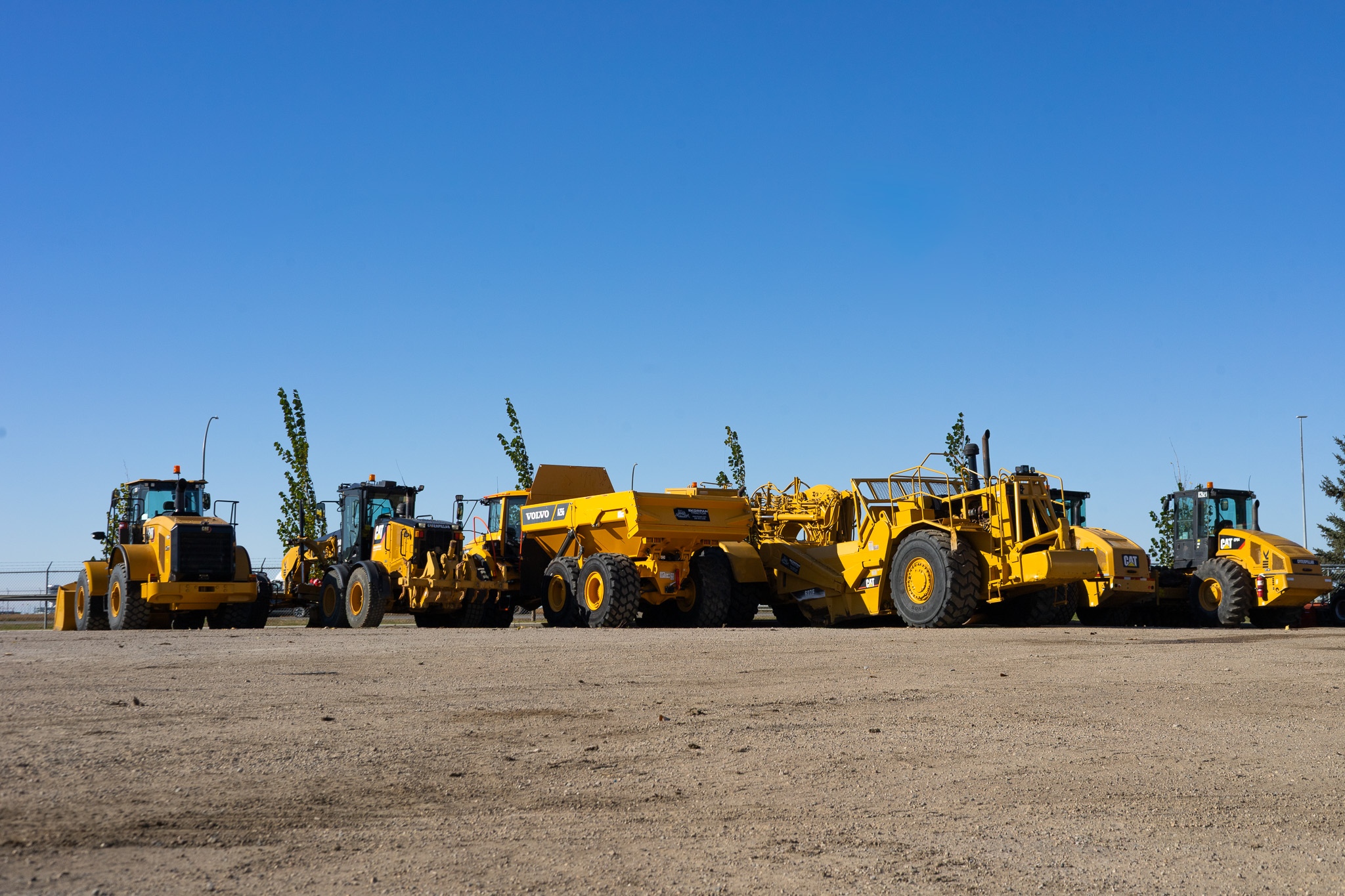 Lineup of Korpan Tractor heavy equipment under a blue sky