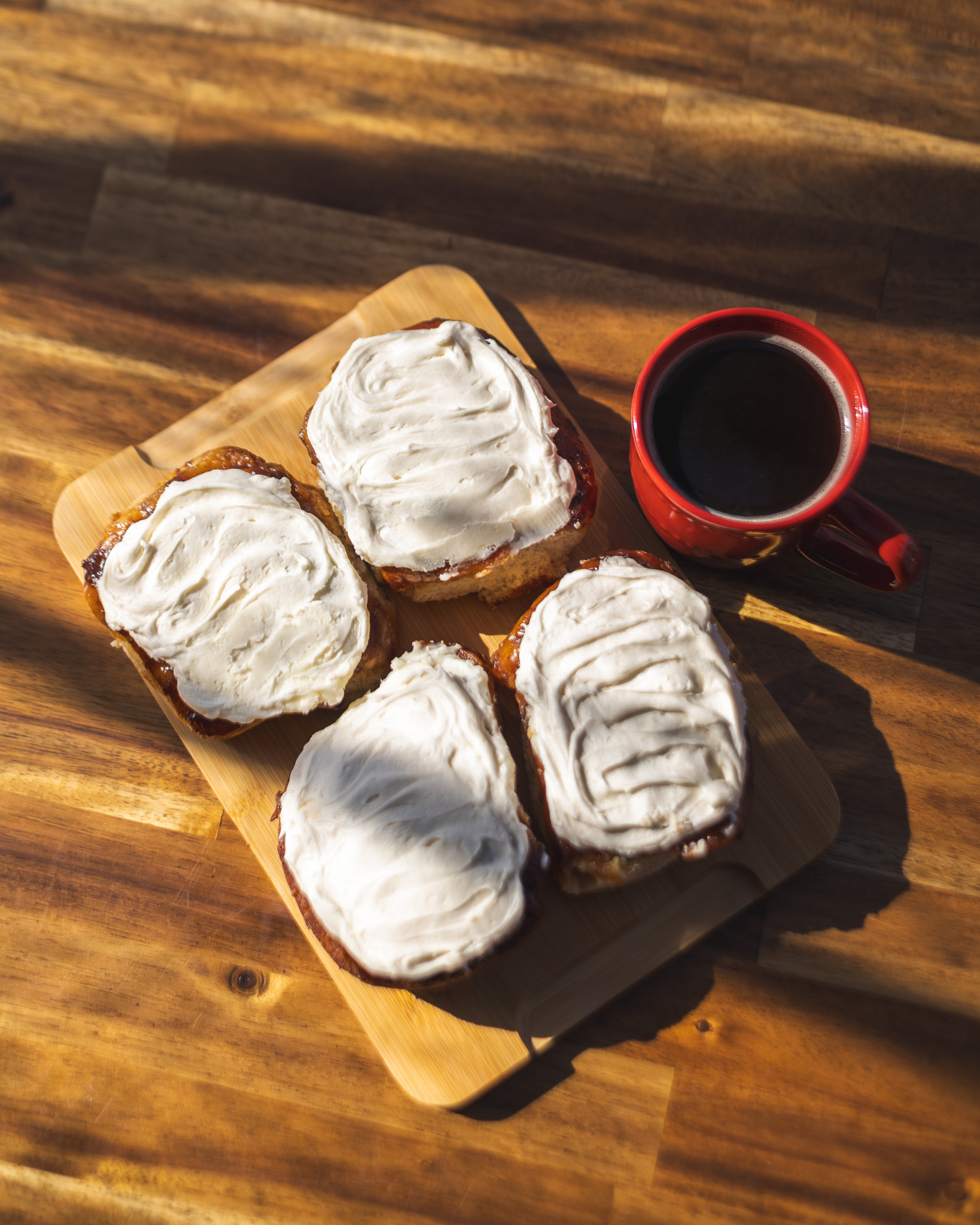 Frosted cinnamon buns served with a red coffee mug